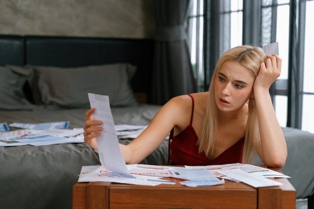 A young adult looking stressed while surrounded by bills and debt-related documents. The image conveys the emotional and financial burden of debt, highlighting the importance of financial literacy and responsible money management.