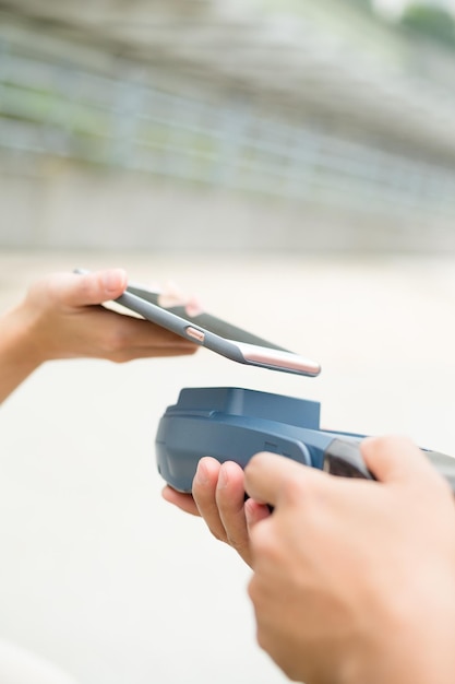 A hand inserting a credit card into a card reader, with a smartphone displaying a balance transfer offer in the background.