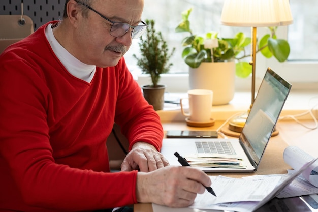 A person using a laptop to review financial documents and spreadsheets, with a focus on calculating retirement savings and projecting future income, emphasizing careful financial planning.