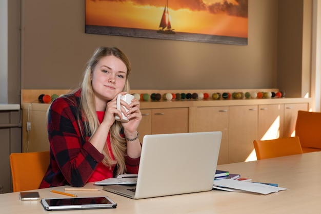 A woman reviewing her budget on a laptop while enjoying a cup of coffee at home. The scene is relaxed, showing that managing finances can be a part of everyday life.