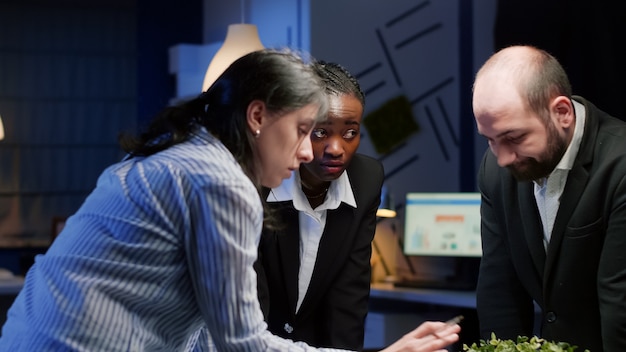 A diverse group of people sitting around a table, engaged in a lively discussion about financial planning, with charts and graphs displayed on a screen.