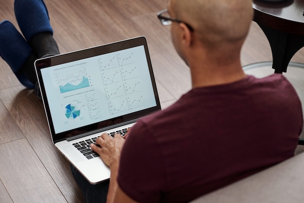 An image of a person using a laptop with a spreadsheet visible on the screen, illustrating budgeting and financial planning. The background includes visual elements such as a calculator, a notebook, and graphs, representing financial analysis.