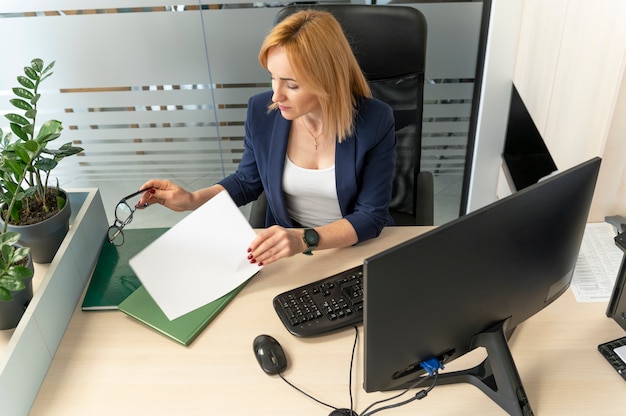 A person reviewing paperwork at a desk, with a computer displaying insurance comparison charts.