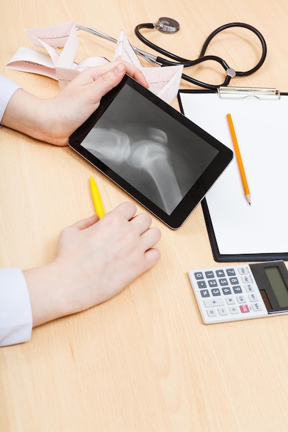 A person sitting at a desk, calculating potential healthcare costs with a calculator and a list of common vision and dental procedures on a notepad.