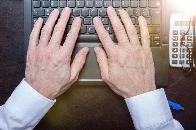 A person's hands typing on a laptop keyboard with focus on the fingers and keys, symbolizing the digital process of managing a brokerage account and making investment decisions online.