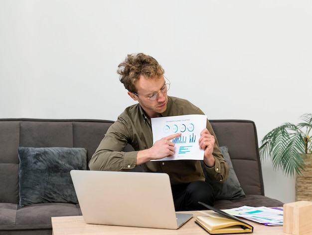 A person reviewing paperwork at a desk with a laptop displaying investment account growth charts, emphasizing financial planning and informed decision-making.