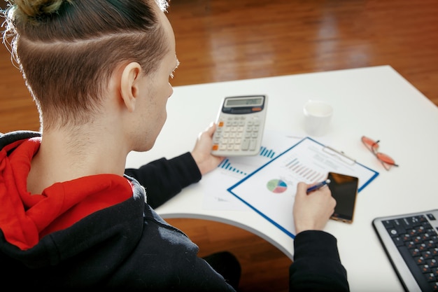 A person using a calculator and reviewing financial documents, with a spreadsheet showing potential tax savings from 529 plan contributions.