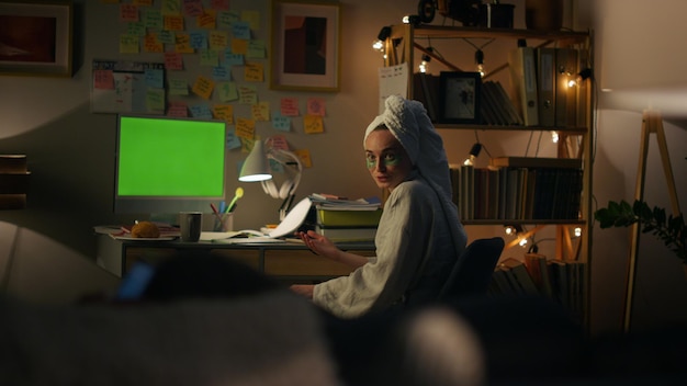 A student creating a crowdfunding campaign video in their dorm room, surrounded by books and a laptop. The scene is brightly lit and conveys determination.
